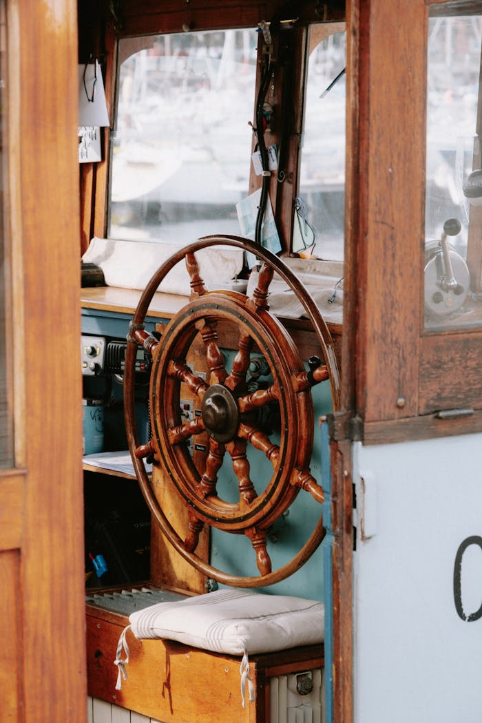 Close-up of a vintage wooden steering wheel inside a boat, capturing a maritime theme.