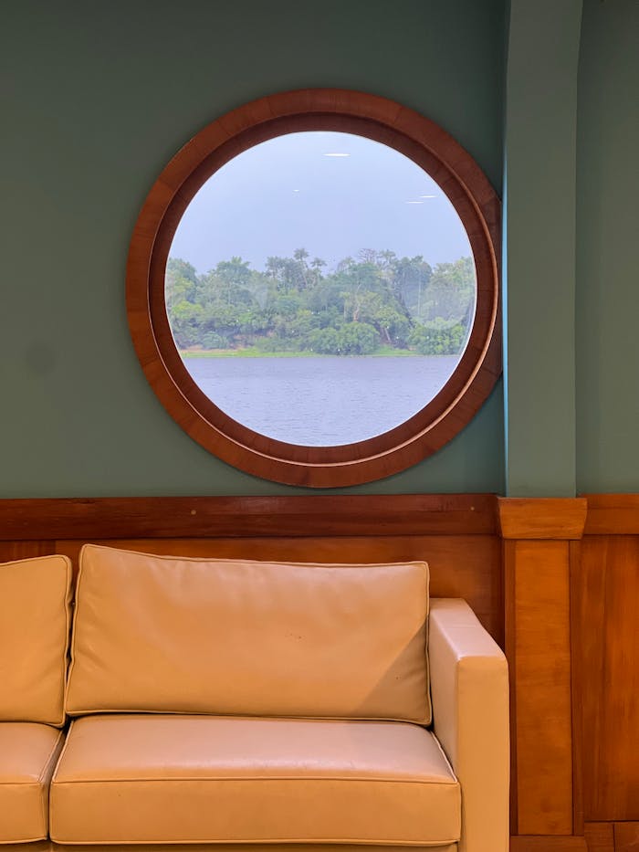 A luxurious ship cabin with leather sofa and view of a river in Brazil.